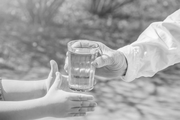 Avó dando um copo de água limpa para uma criança. Foco seletivo
. - Foto, Imagem