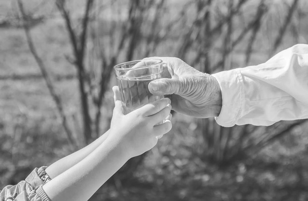 Grand-mère donnant un verre d'eau propre à un enfant. Concentration sélective. - Photo, image