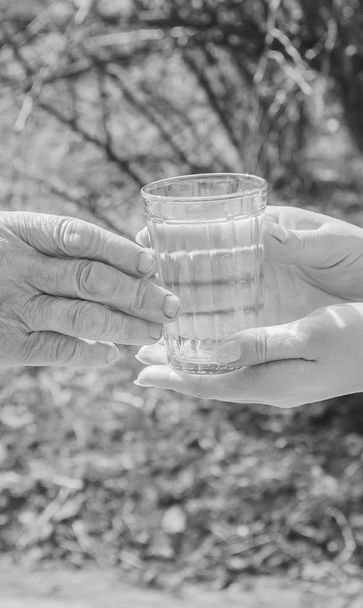 Grand-mère donnant un verre d'eau propre à une femme. Concentration sélective
. - Photo, image