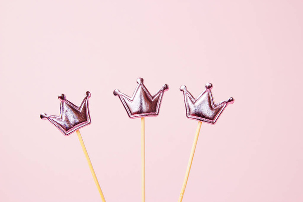 Kolme kiiltävää kruunua vaaleanpunaisella taustalla. Juhlapyhien koristeet. Kopioi tila
 - Valokuva, kuva
