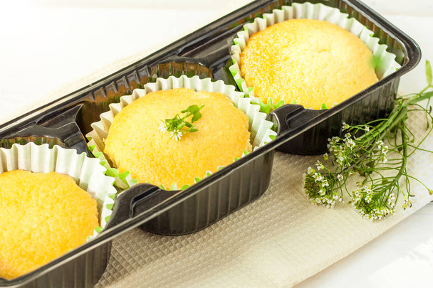Muffins frais faits maison dans la boîte d'emballage sur une table en bois léger
 - Photo, image