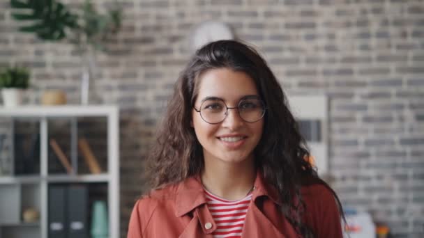 Slow motion portrait of pretty girl employee smiling looking at camera in office - Materiał filmowy, wideo