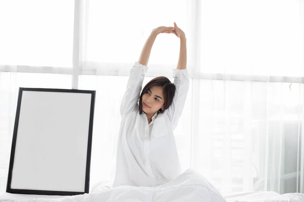 Mujer asiática Hermosa joven sonriente sentada en la cama y str
 - Foto, Imagen