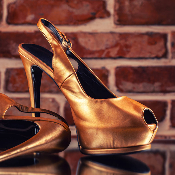 Gold high heels on the red brick wall background - Fotoğraf, Görsel