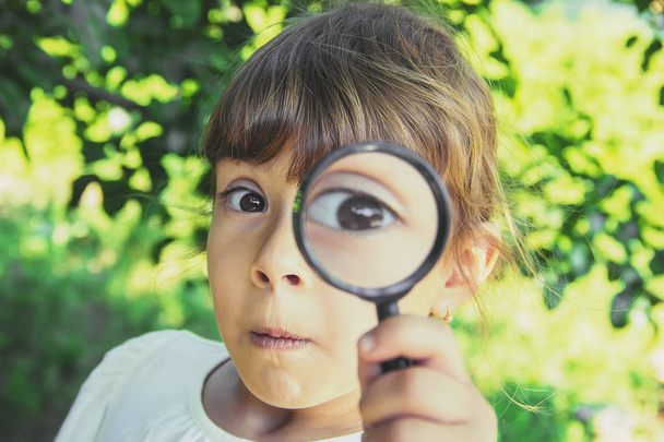 The child is looking in a magnifying glass. Increase. selective focus. - Fotoğraf, Görsel