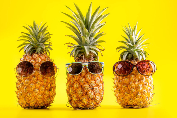 Creative pineapple looking up with sunglasses and shell isolated on yellow background, summer vacation beach idea design pattern, copy space close up - Fotografie, Obrázek
