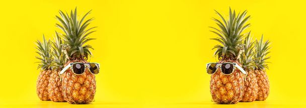 Δημιουργική ανανά κοιτάζοντας πάνω με γυαλιά ηλίου και κέλυφος απομονώνονται σε κίτρινο φόντο, καλοκαιρινές διακοπές παραλία σχέδιο ιδέα σχέδιο, αντίγραφο χώρου κοντά - Φωτογραφία, εικόνα