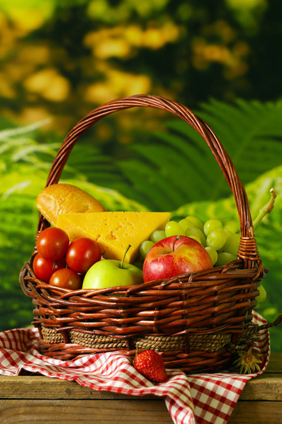 basket with picnic products on a wooden background - Foto, afbeelding