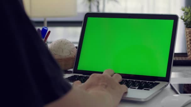 Женщина, работающая на ноутбуке с зеленым экраном дома. Хрома-ключ. Вид сзади
.  - Кадры, видео