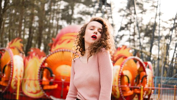 Stylish young hipster woman posing outdoors on the background of carousels - Foto, Bild