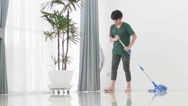 Close up Asiatico giovane ragazzo aiuto famiglia pulizia il casa utilizzando un mop
.  - Filmati, video