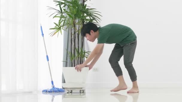 Bliska Azji młody chłopak pomaga rodzinie sprzątanie domu za pomocą MOP.  - Materiał filmowy, wideo