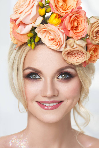 Beauty portrait of a cute blonde girl with a wreath of tea roses. - Photo, Image