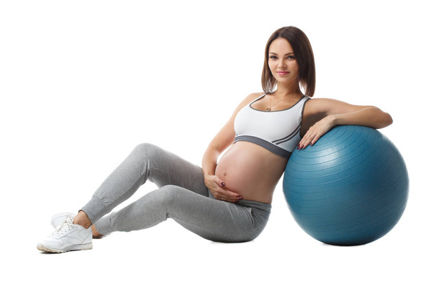 Slender pregnant girl performs fitness exercises with a ball isolated on a white background. - Foto, Imagem