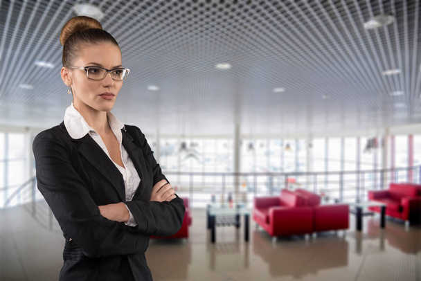 Красивая серьезная деловая женщина в очках на фоне пустого дилерского центра
 - Фото, изображение