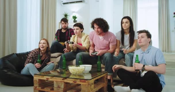 Very excited multi ethnic friends in living room watching how their two friends are on a video game , some of them are the winner - Filmagem, Vídeo