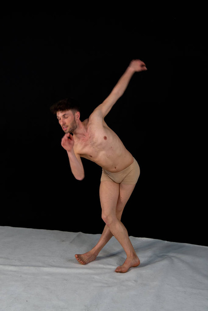 Гімнастичні пози Кавказького танцю людини в студії з пластиковими рук і ніг позиції. Привабливий молодий чоловік показує сучасні танцювальні пози, на чорному фоні. - Фото, зображення