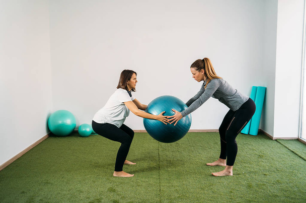 Pregnant woman doing fitness ball and pilates exercise with coac - Zdjęcie, obraz