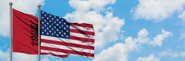 一緒に白い曇り青い空に対して風に手を振るアルバニアと米国の旗。外交概念、国際関係. - 写真・画像