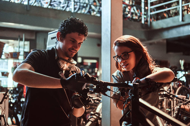 Young master and his attractive apprentice are fixing customers bicycle at workshop - Fotoğraf, Görsel