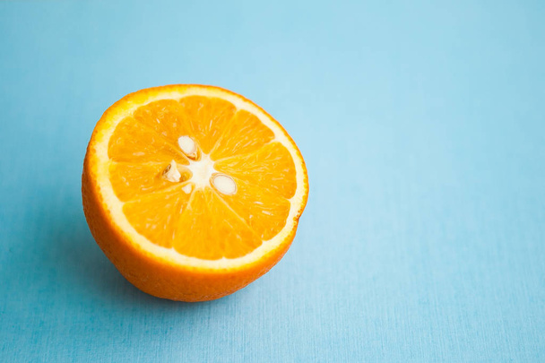 Half of orange on light blue background - Foto, afbeelding