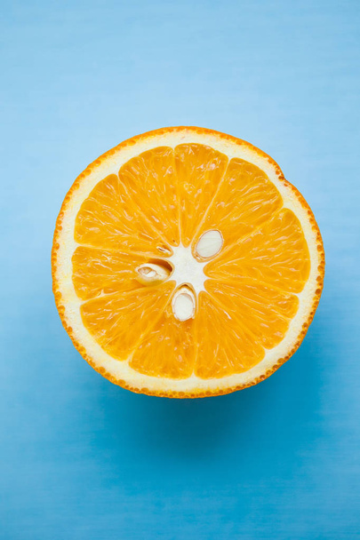 Half of orange on light blue background - Valokuva, kuva