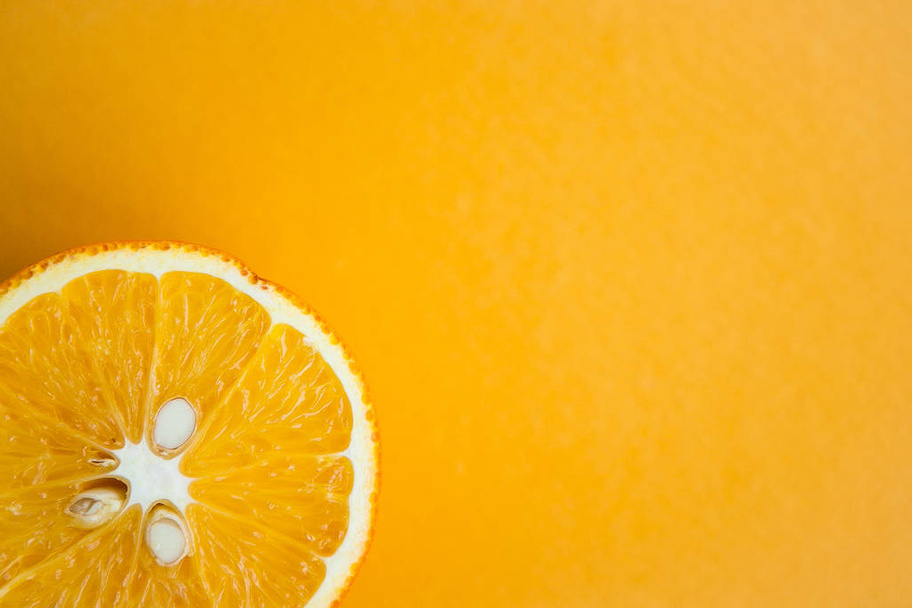Mitad de naranja sobre fondo amarillo
 - Foto, Imagen