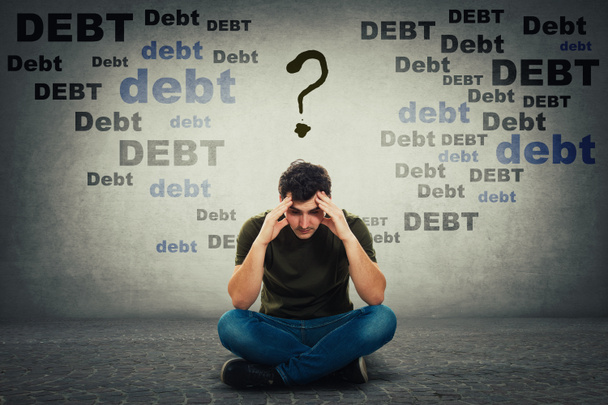 upset man looking down thoughtful surrounded by huge debt amount - Photo, Image