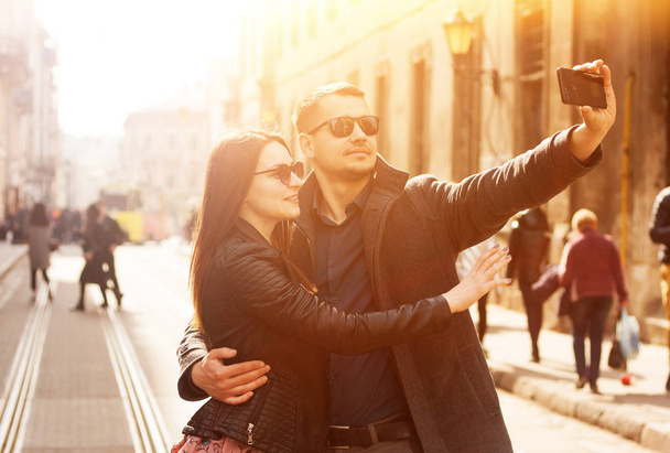 Happy couple making selfie in the street. Toned sunny picture. - 写真・画像