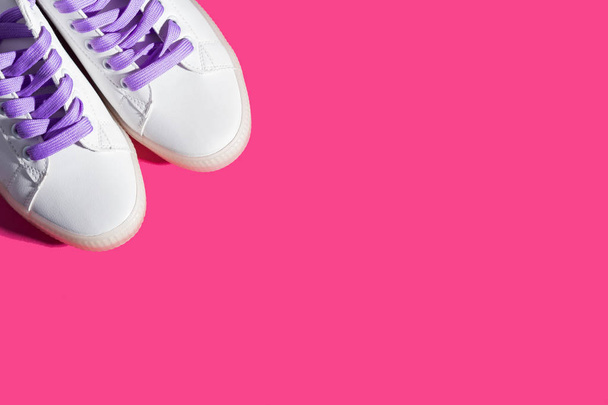 White sneakers with purple laces on bold pink - 写真・画像