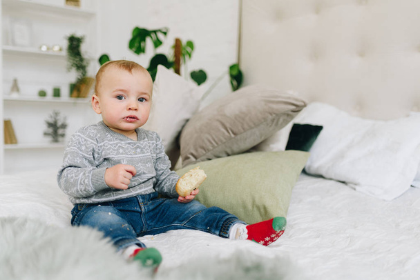Schattige kleine peuter jongen zittend op bed houden van een snack - Foto, afbeelding