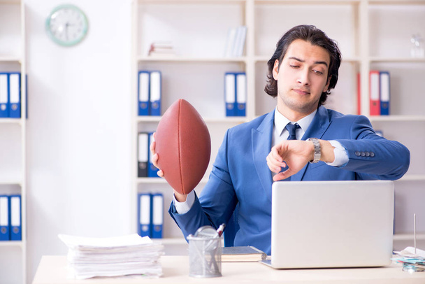 Giovane bell'uomo d'affari con palla da rugby in ufficio
 - Foto, immagini