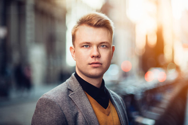 Handsome young adult businessman portrait outdoors on city street at sunset time - Photo, image