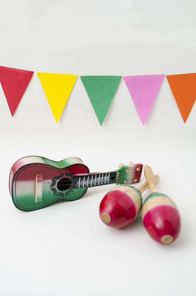 Toy guitar, maracas and colorful flags on white background. Objects for Cinco de Mayo or Independence Day celebration - Photo, Image