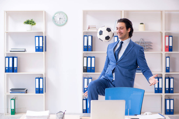 Jeune homme d'affaires beau avec ballon de football dans le bureau
  - Photo, image