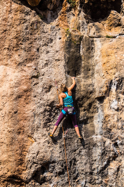 Een meisje klimt op een rots. - Foto, afbeelding