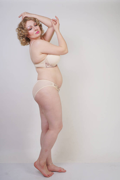 Ładna kaukaski Chubby kobieta z ciała plus rozmiar i blady skóry noszenie bielizny moda na białym tle Studio - Zdjęcie, obraz