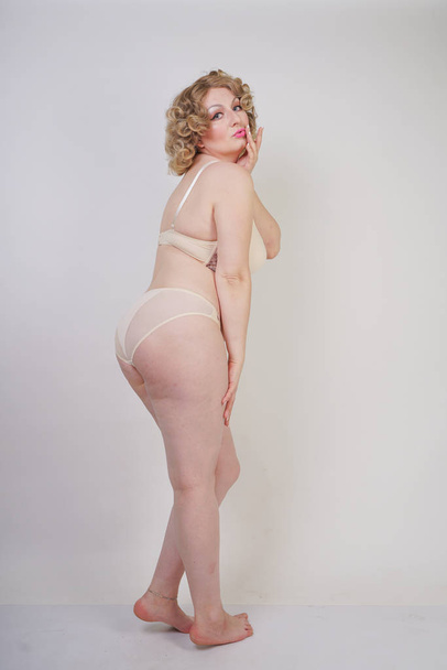 jolie femme potelée caucasienne avec corps taille plus et peau pâle portant lingerie de mode sous-vêtements sur fond de studio blanc
 - Photo, image