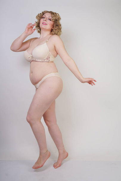 pretty caucasian chubby woman with plus size body and pale skin wearing underwear fashion lingerie on white studio background - 写真・画像