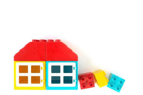 Σπίτι κατασκευασμένο από μικρά και μεγάλα πλαστικά τούβλα κατασκευαστή σε λευκό φόντο. Δημοφιλή παιχνίδια. - Φωτογραφία, εικόνα