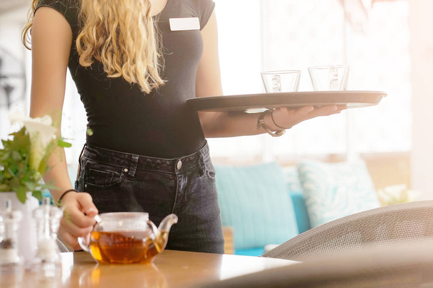 Chica trabajando como camarera sosteniendo una bandeja con té
 - Foto, Imagen