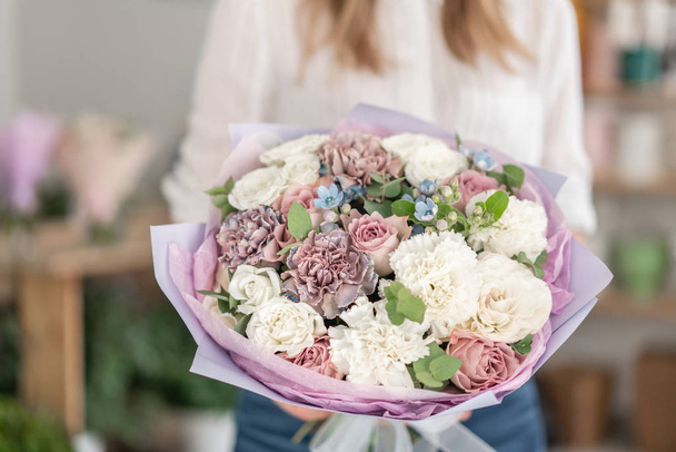 Beautiful bouquet of mixed flowers in woman hand. the work of the florist at a flower shop. Delicate Pastel color. Fresh cut flower. White and lilac color - Foto, afbeelding