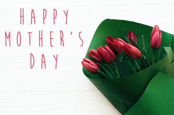 Happy Mother 's Day text and beautiful red tulips on white wooden
 - Фото, изображение