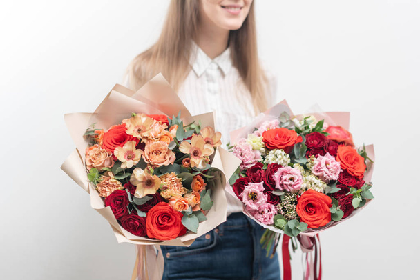 女性の手に混合花の2つの美しい花束。花屋の花屋さんの仕事繊細なパステルカラー。切りたての花赤と桃の色 - 写真・画像