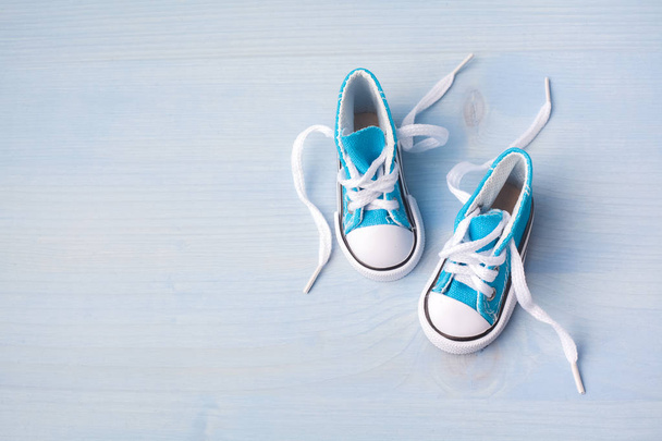 Cute tiny baby shoes on a wooden background with space for text. Top view - Foto, Imagen