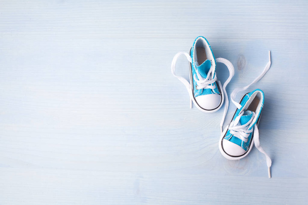 Cute tiny baby shoes on a wooden background with space for text. Top view - Foto, Imagen