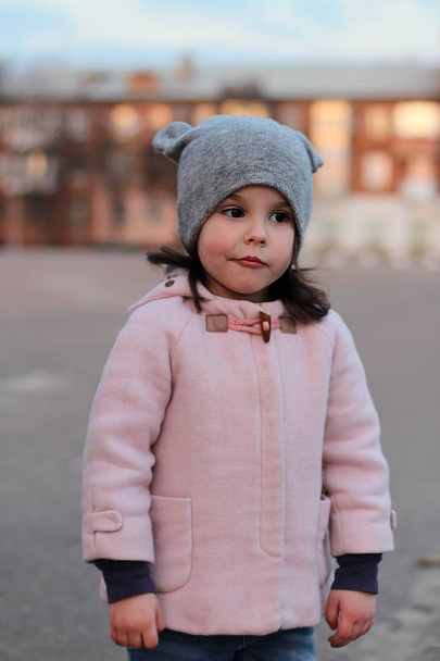 Πρόσβαλε ένα μικρό λευκό κορίτσι που περπατούσε στο δρόμο το βράδυ. Πορτραίτο στο φόντο του τοπίου του ηλιοβασιλέματος - Φωτογραφία, εικόνα