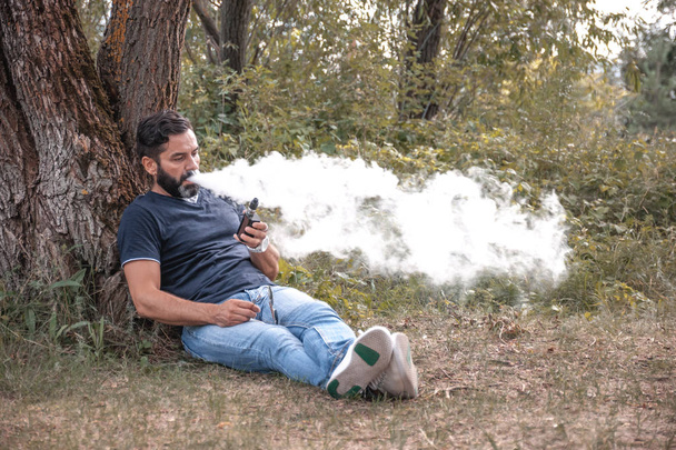 Hombre fumando un cigarrillo electrónico al aire libre
 - Foto, imagen