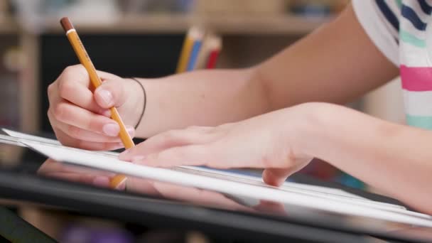 Girls hands drawing something on a piece of paper with a pencil - Video