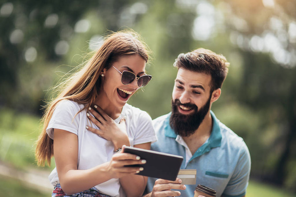 Heureux couple payant en ligne avec carte de crédit et tablette numérique
  - Photo, image